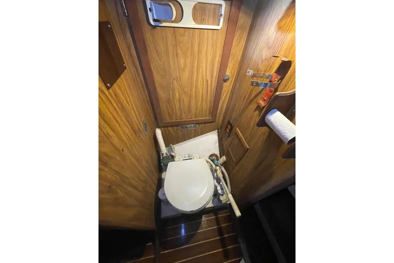 Slide: The Image of 1977 Custom Bodega 30 boat bathroom with wooden paneling and compact toilet. - 18