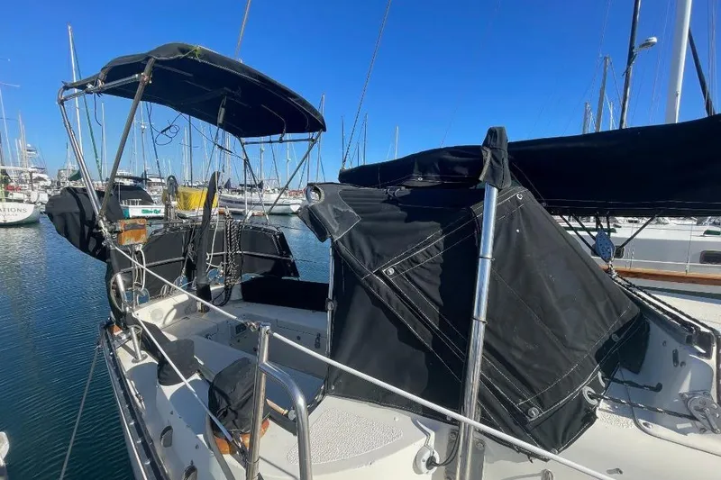 Slide: The Image of 1977 Custom Bodega 30 sailboat with black canopy docked in marina. - 2