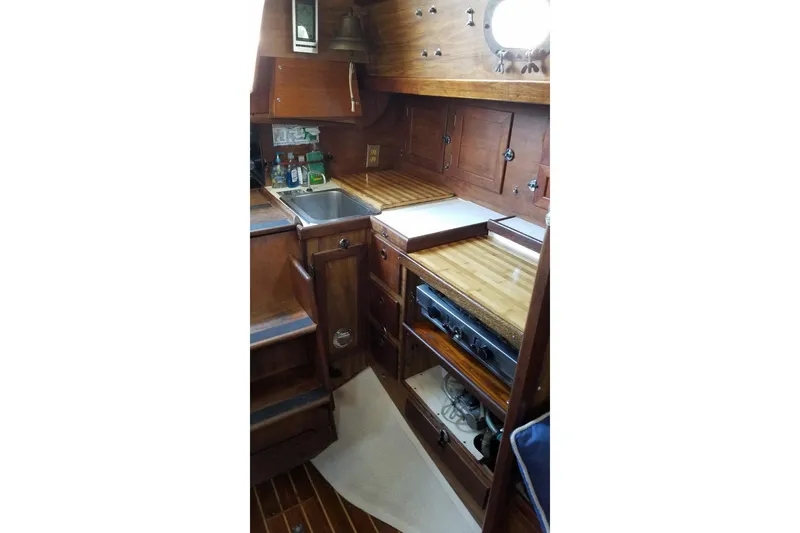 Slide: The Image of 1977 Custom Bodega 30 yacht interior with wooden cabinetry and compact kitchen area. - 22