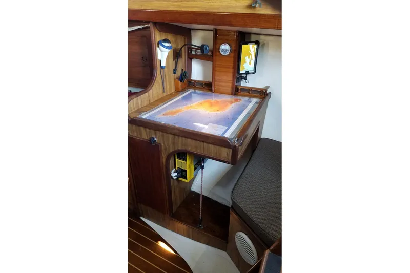Slide: The Image of Navigation station inside a 1977 Custom Bodega 30 sailboat, featuring a nautical chart. - 24