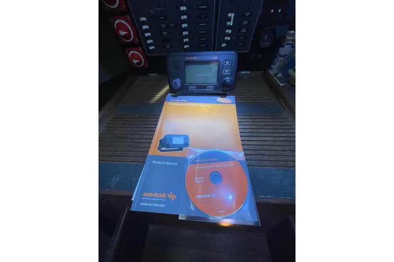 Slide: The Image of Em-trak AIS transceiver with manual and CD on a Custom Bodega 30, 1977 model. - 36