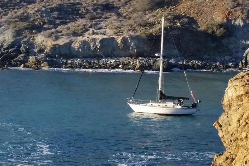 Slide: The Image of Sailboat "Bodega 30" from 1977 anchored near rocky coastline. - 41