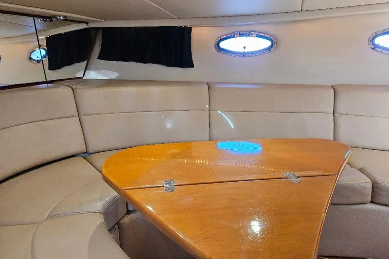 Slide: The Image of Interior of 2010 Regal 3350 Cuddy with beige seating and wooden table. - 6