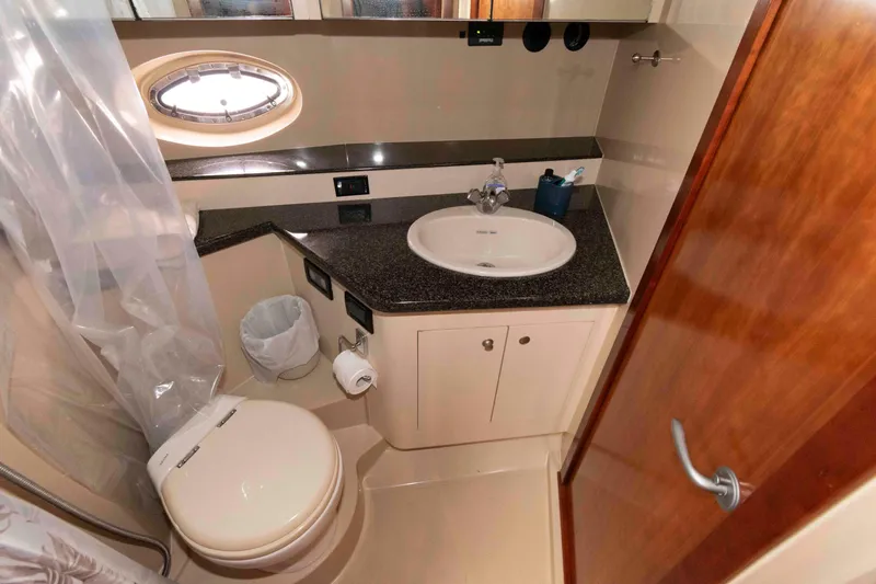 Slide: The Image of 2007 Cruisers Yachts 460 Express bathroom with sink, toilet, and porthole window. - 21
