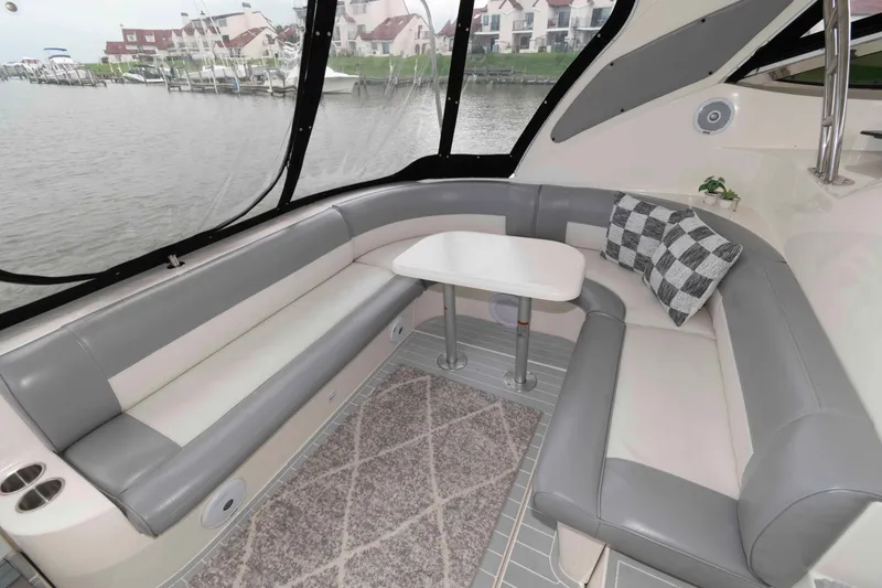Slide: The Image of 2007 Cruisers Yachts 460 Express interior with gray seating, table, and waterfront view. - 8