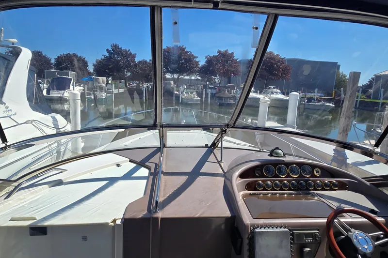 Slide: The Image of Interior of 2004 Regal Commodore 3260 boat with seating and table, docked near a red truck. - 34