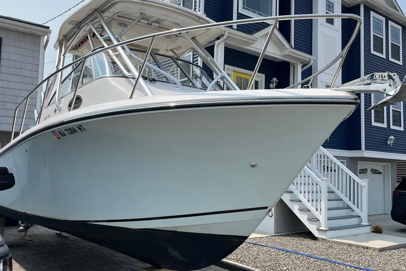 Slide: The Image of 2011 Sailfish 2660 WAC boat parked near blue house, showcasing sleek design. - 14