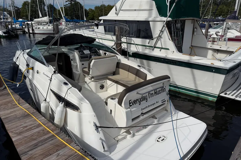 Slide: The Image of 2015 Sea Ray 260 Sundancer docked at marina, featuring open cockpit and seating. - 1