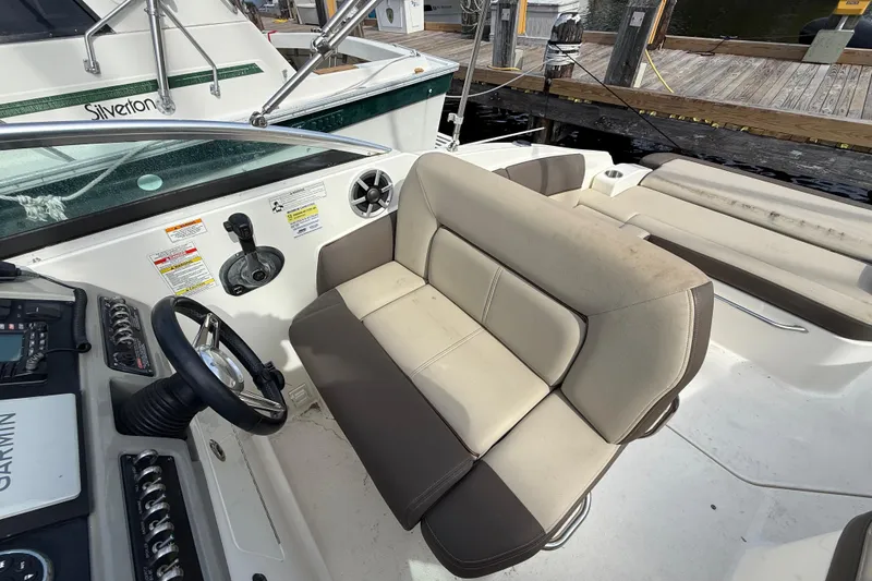Slide: The Image of 2015 Sea Ray 260 Sundancer cockpit with beige seating and steering wheel, docked at marina. - 10
