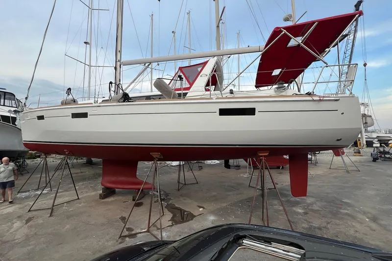 Slide: The Image of 2013 Beneteau Oceanis 45 sailboat on stands, red hull, marina setting. - 4