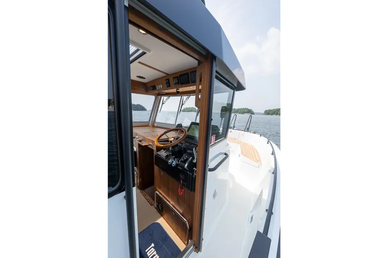 Slide: The Image of 2026 Targa 32 GT boat interior with wooden dashboard and steering wheel on open water. - 18