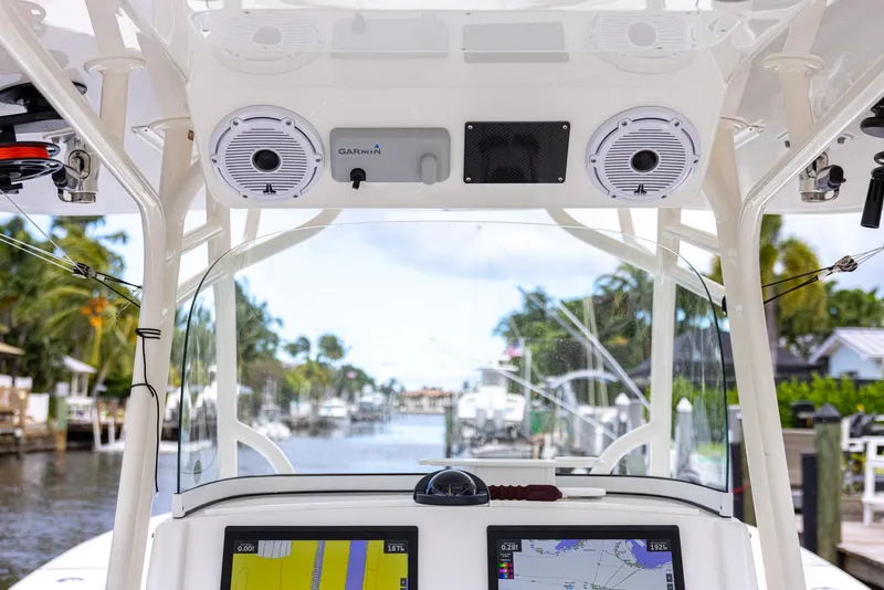 Slide: The Image of 2019 Regulator 34 boat dashboard with navigation screens and speakers, docked in a scenic marina. - 11