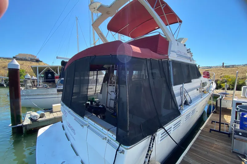 Slide: The Image of 1989 Bayliner 3888 Motoryacht docked at marina with red canopy and black mesh enclosure. - 29