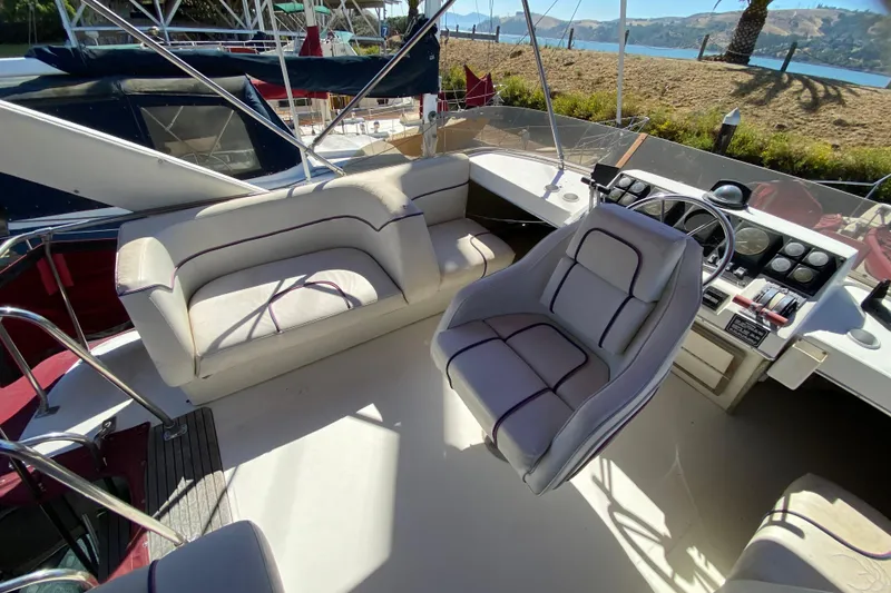 Slide: The Image of 1989 Bayliner 3888 Motoryacht cockpit with helm, seating, and scenic waterfront view. - 6