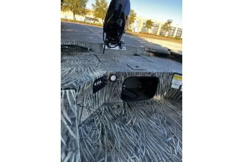 Slide: The Image of 2026 Tracker Grizzly 1654 T Sportsman boat with camo design and motor, parked outdoors. - 4