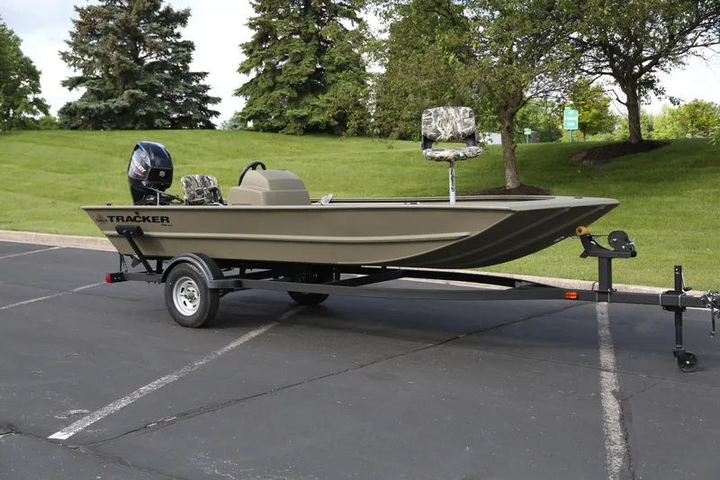 The Image of 2026 Tracker Grizzly 1754 SC boat on trailer, parked outdoors with green trees in background. - 0