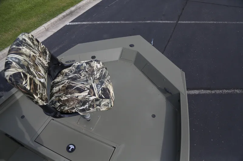 Slide: The Image of 2026 Tracker Grizzly 1754 SC boat with camo seat on a paved surface. - 2