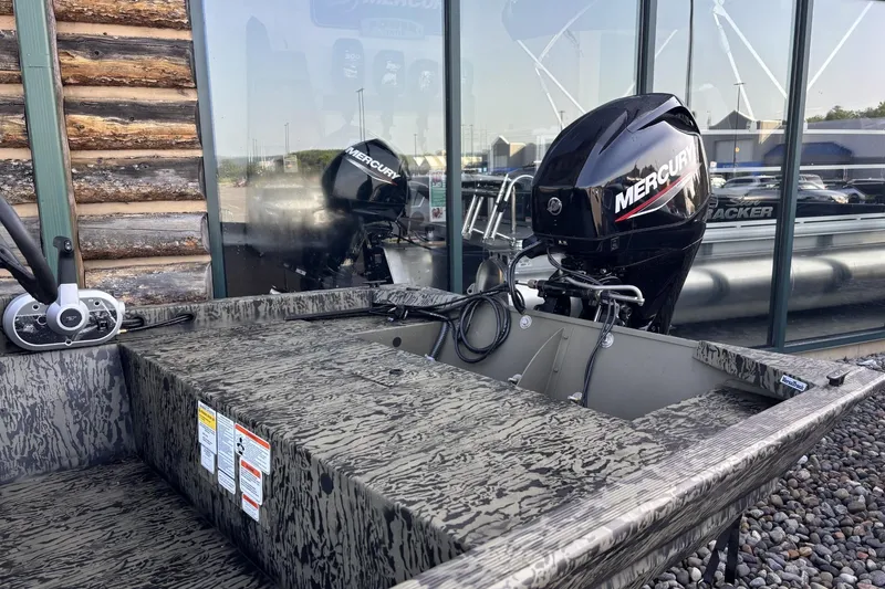 Slide: The Image of 2026 Tracker Grizzly 1648 SC boat with Mercury outboard motor, parked outdoors. - 2