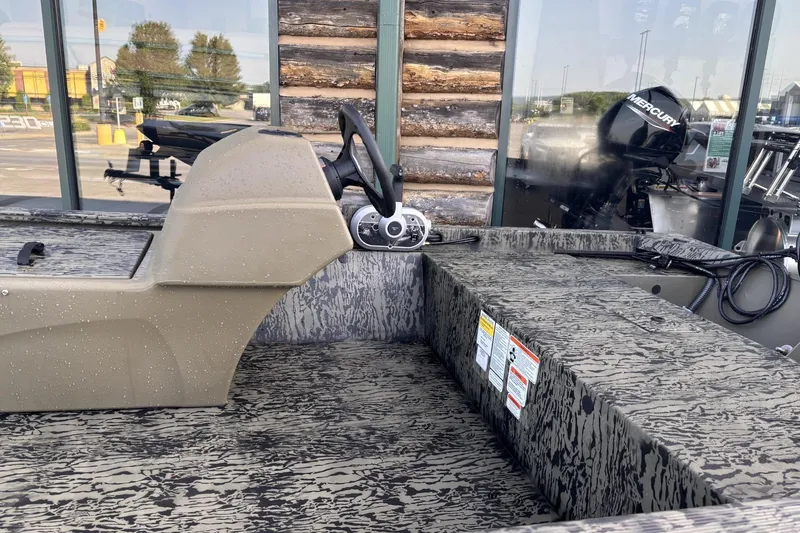 Slide: The Image of 2026 Tracker Grizzly 1648 SC boat interior with steering console and camouflage seating. - 4