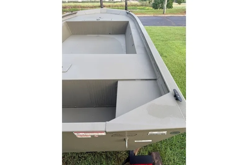Slide: The Image of 2026 Tracker Grizzly 1754 Utility boat on grass, showcasing interior seating and storage. - 6