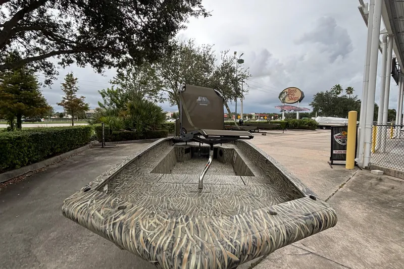 Slide: The Image of 2026 Tracker Grizzly 1650 T Prairie Wings Edition boat in a parking lot, camo design. - 2