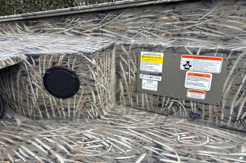 Slide: The Image of 2026 Tracker Grizzly 1650 T Prairie Wings Edition interior with camouflage design and safety labels. - 14