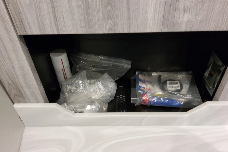 Slide: The Image of Storage compartment with various items in a 2026 Formula 380 Super Sport Crossover OB. - 121