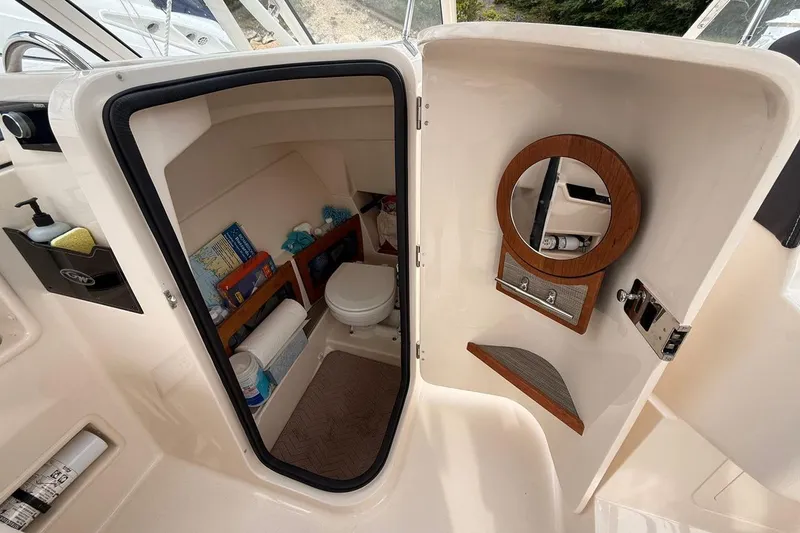 Slide: The Image of 2025 Grady-White Freedom 235 boat interior with compact bathroom and storage shelves. - 14