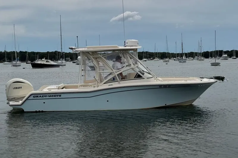 Slide: The Image of 2025 Grady-White Freedom 235 boat on calm water, surrounded by sailboats. - 2