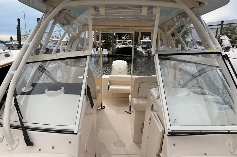 Slide: The Image of 2025 Grady-White Freedom 235 boat interior with seating and windshield, docked at marina. - 7