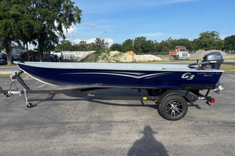 Slide: The Image of 2025 G3 Guide V16 XT boat on trailer, parked outdoors under clear sky. - 6