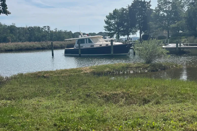 Slide: The Image of 2012 Sabre 42 Salon Express yacht docked in a serene, tree-lined waterway. - 32