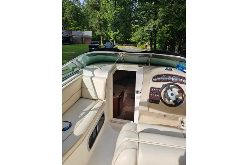 Slide: The Image of 2002 Chaparral Signature 240 boat interior with steering wheel and seating, surrounded by trees. - 5