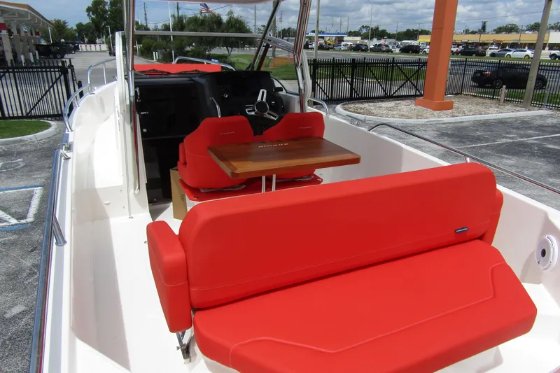 Slide: The Image of 2024 Nimbus T8 boat with vibrant red seating and wooden table in cockpit area. - 34