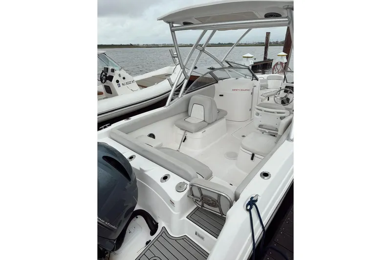 Slide: The Image of 2022 Seafox 226 Traveler boat interior with seating and steering wheel, docked by the water. - 5