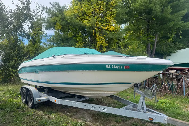 The Image of 1991 Sea Ray 220 boat on trailer, covered, surrounded by trees. - 0