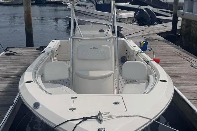 Slide: The Image of 2024 Cobia 220 Center Console boat docked at marina, showcasing sleek design and spacious seating. - 2