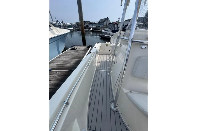 Slide: The Image of 2024 Cobia 220 Center Console boat docked at marina, showcasing sleek deck design. - 7