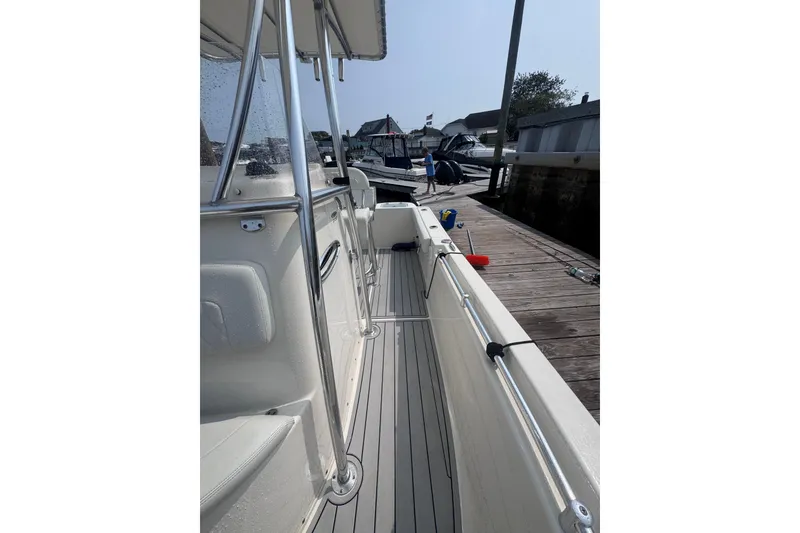 Slide: The Image of 2024 Cobia 220 Center Console boat docked, showcasing sleek design and spacious deck. - 9