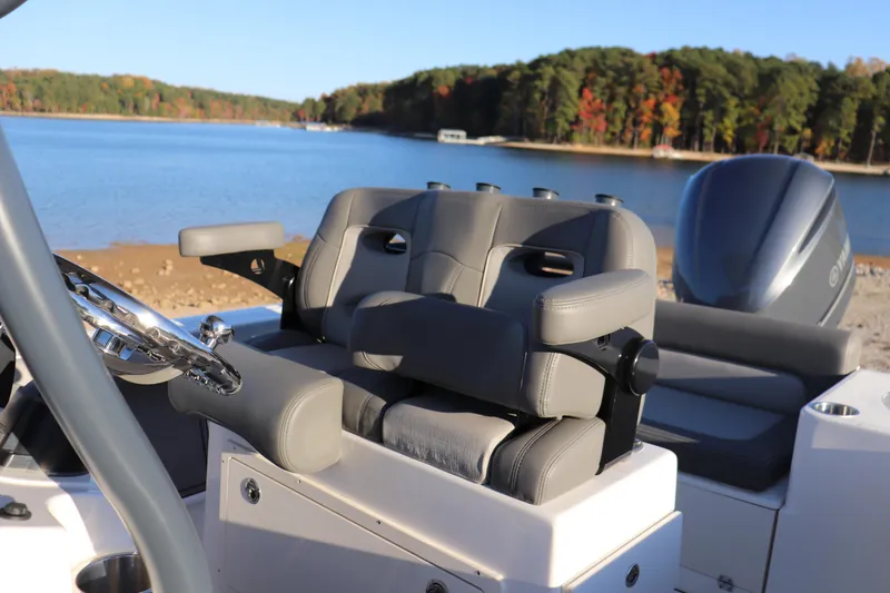 Slide: The Image of 2024 Sea Born LX22 Center Console boat interior with gray seating, steering wheel, and scenic lake view. - 9
