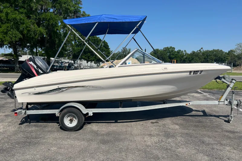 Slide: The Image of 2000 Wellcraft Capri boat on trailer with blue canopy, parked outdoors. - 13