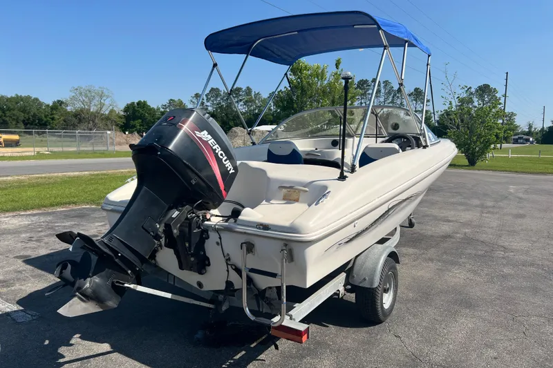 Slide: The Image of 2000 Wellcraft Capri boat with Mercury outboard motor on a trailer, parked outdoors. - 4