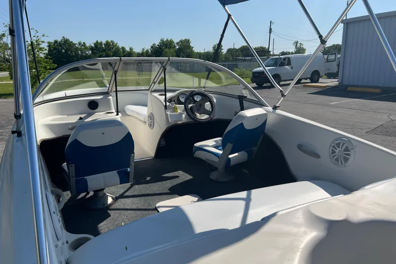 Slide: The Image of 2000 Wellcraft Capri boat interior with blue and white seating, parked outdoors. - 8
