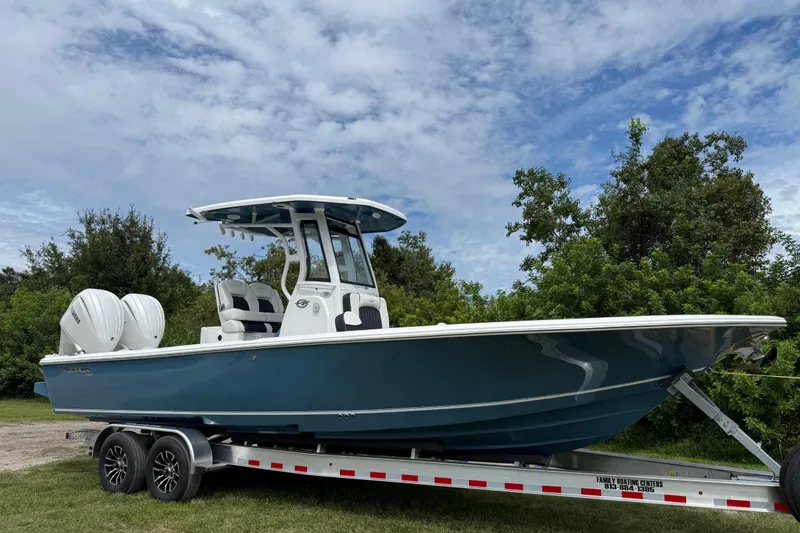 The Image of 2026 Tidewater 2700 Carolina Bay boat on trailer, surrounded by greenery and blue sky. - 0
