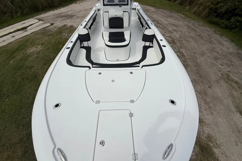 Slide: The Image of 2026 Tidewater 2700 Carolina Bay boat, white deck, black accents, parked on grassy terrain. - 19