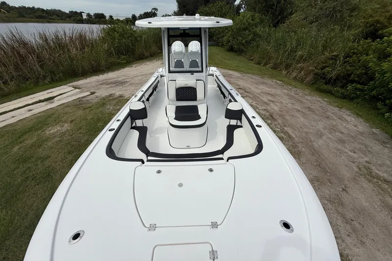 Slide: The Image of 2026 Tidewater 2700 Carolina Bay boat on grassy shore near water and trees. - 20