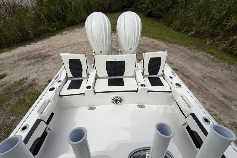 Slide: The Image of 2026 Tidewater 2700 Carolina Bay boat interior with seating and dual engines, parked on grass. - 26