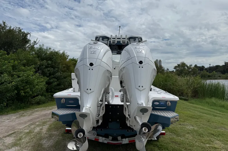 Slide: The Image of 2026 Tidewater 2700 Carolina Bay boat with dual outboard engines, parked on grassy area. - 3