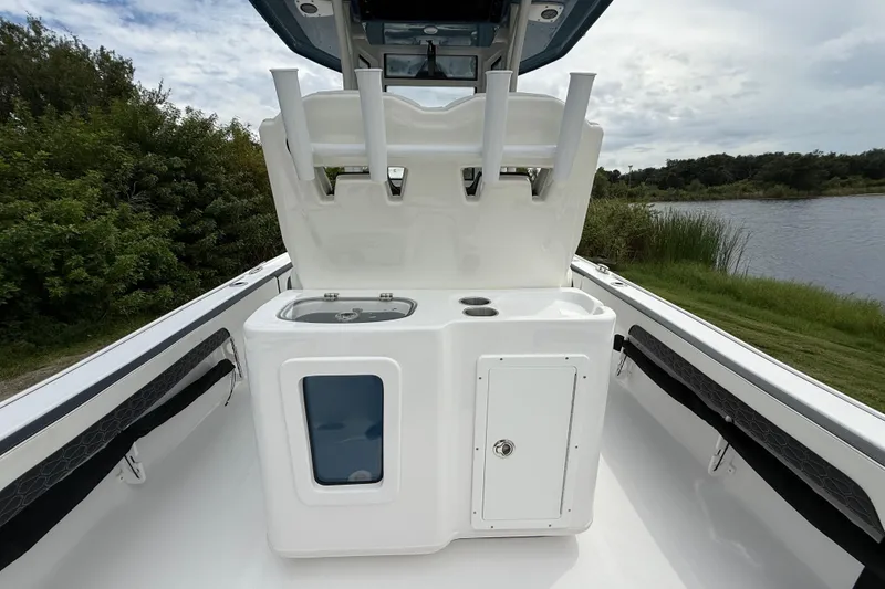 Slide: The Image of 2026 Tidewater 2700 Carolina Bay boat with fishing rod holders and storage, near a serene lake. - 32