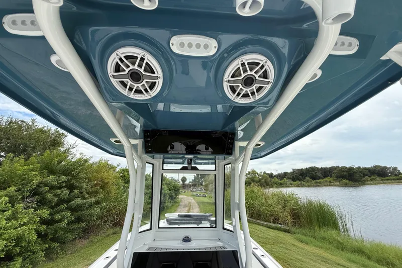 Slide: The Image of 2026 Tidewater 2700 Carolina Bay boat with speakers, viewed from below, near a scenic waterway. - 38